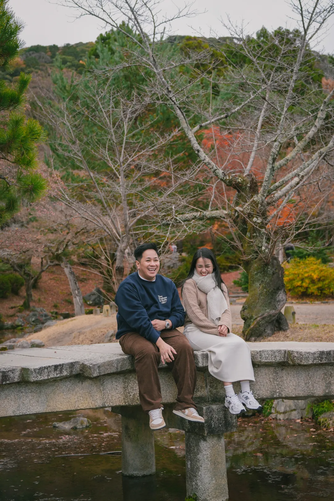 Rein and Mhae laughing together on a stone bridge