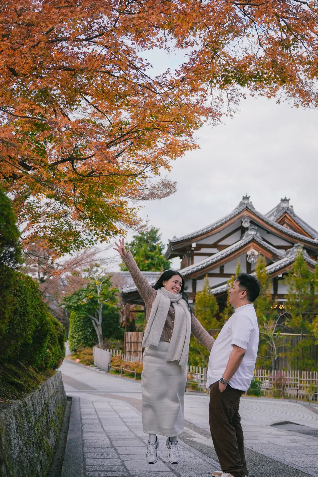 Mhae cheering with her arms up in front of a temple
